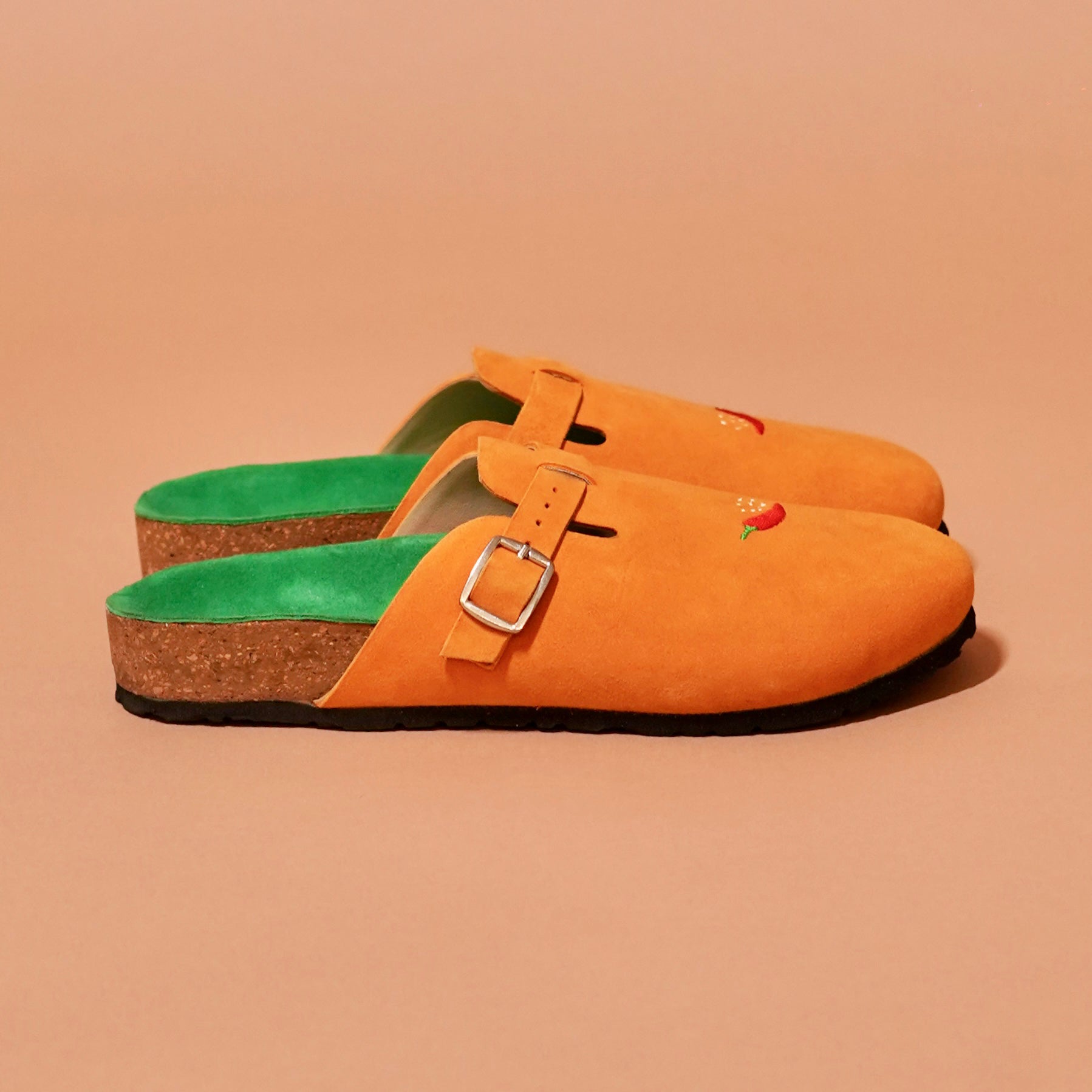 Side profile of Tangerine Mule in orange suede with buckle and embroidery