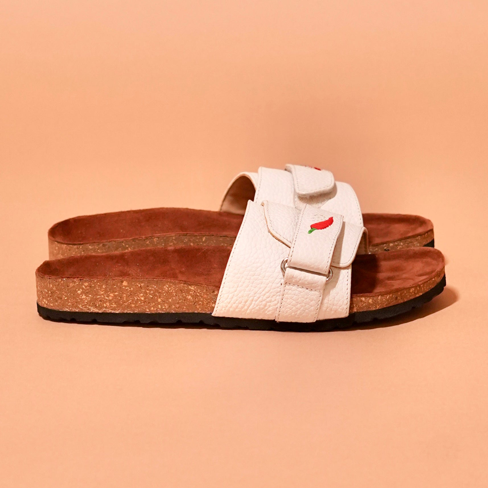 Side view of Salt Slider in white leather with red chilli embroidery