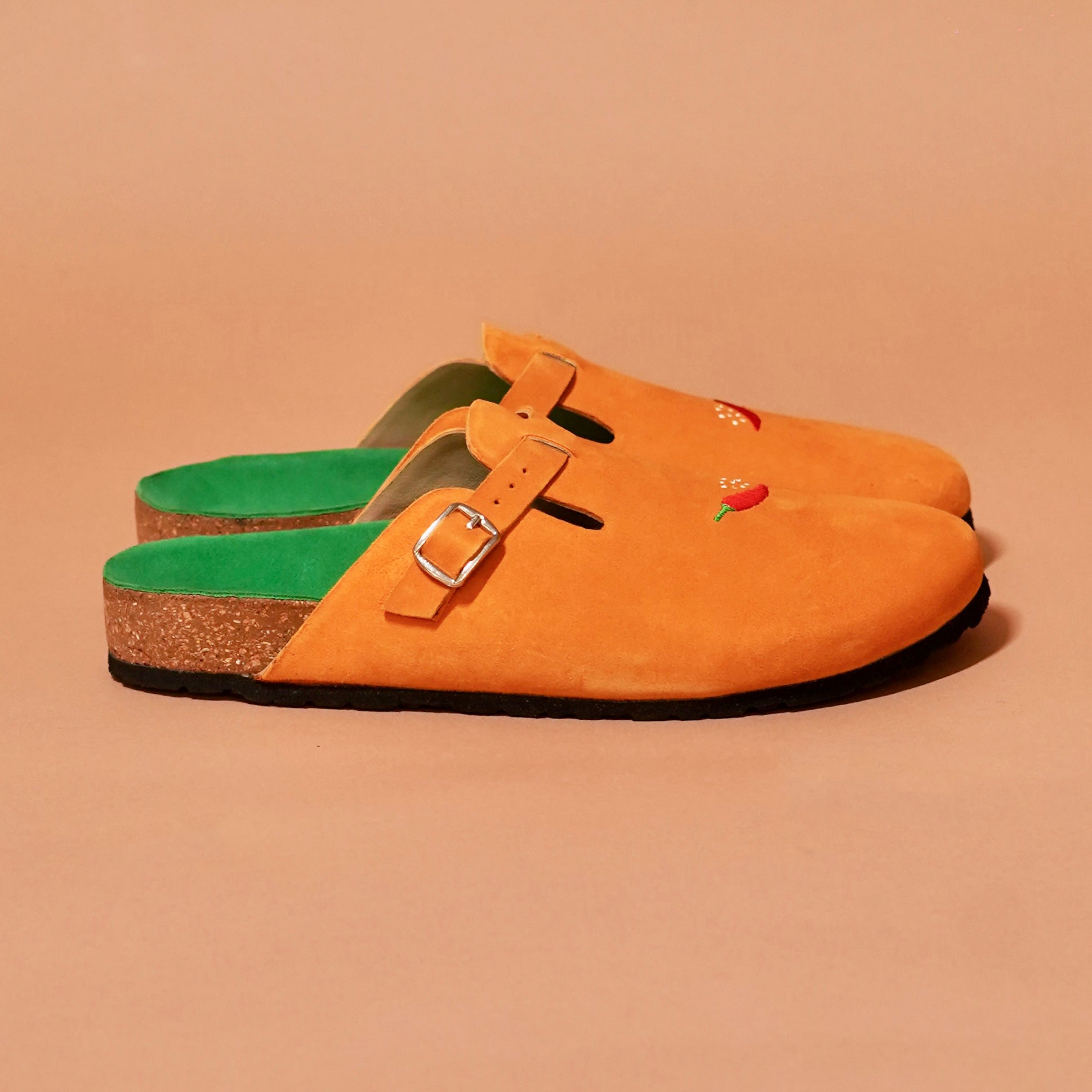 Side profile of Tangerine Mule in orange suede with buckle and embroidery