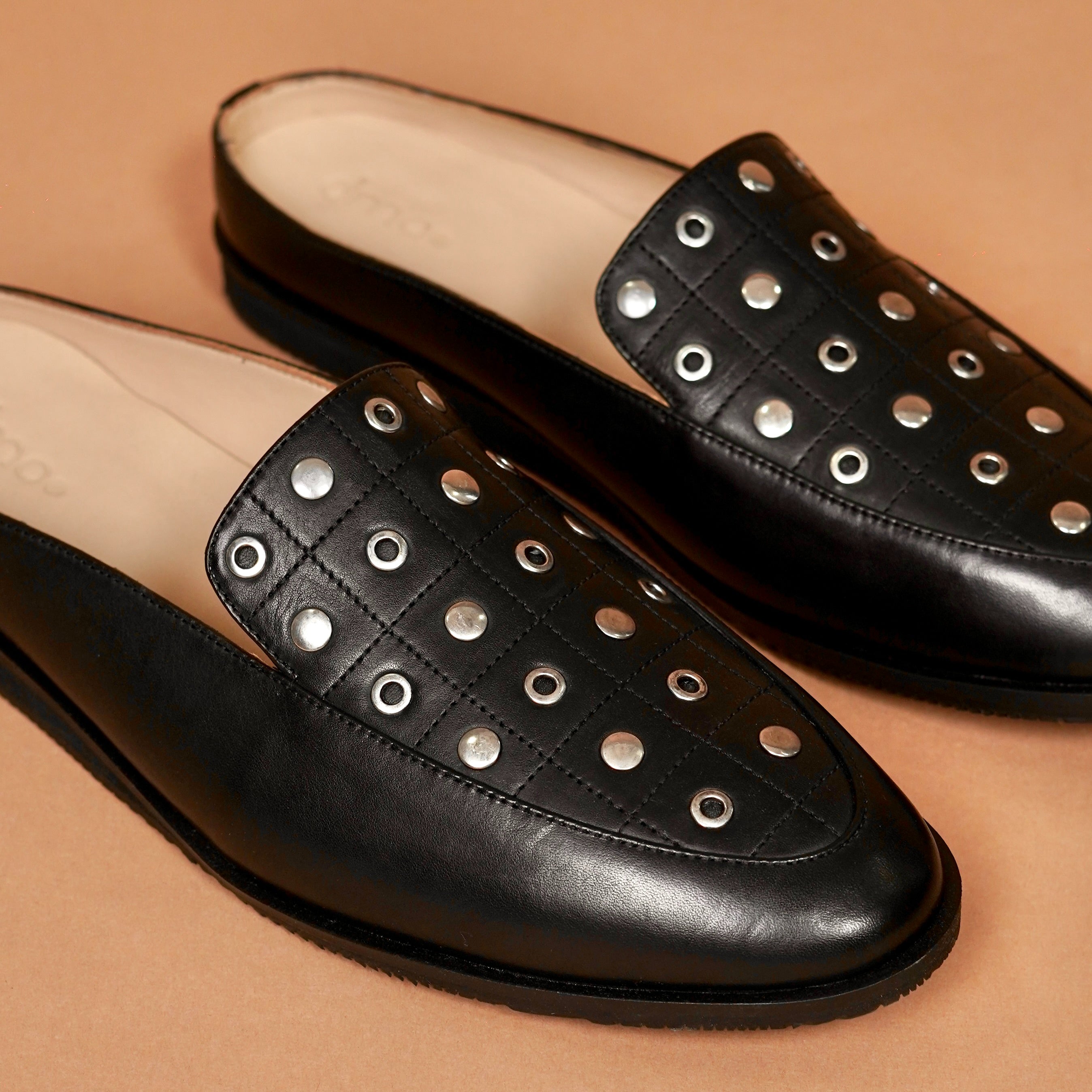 Close-up of silver rivet detailing on black quilted leather