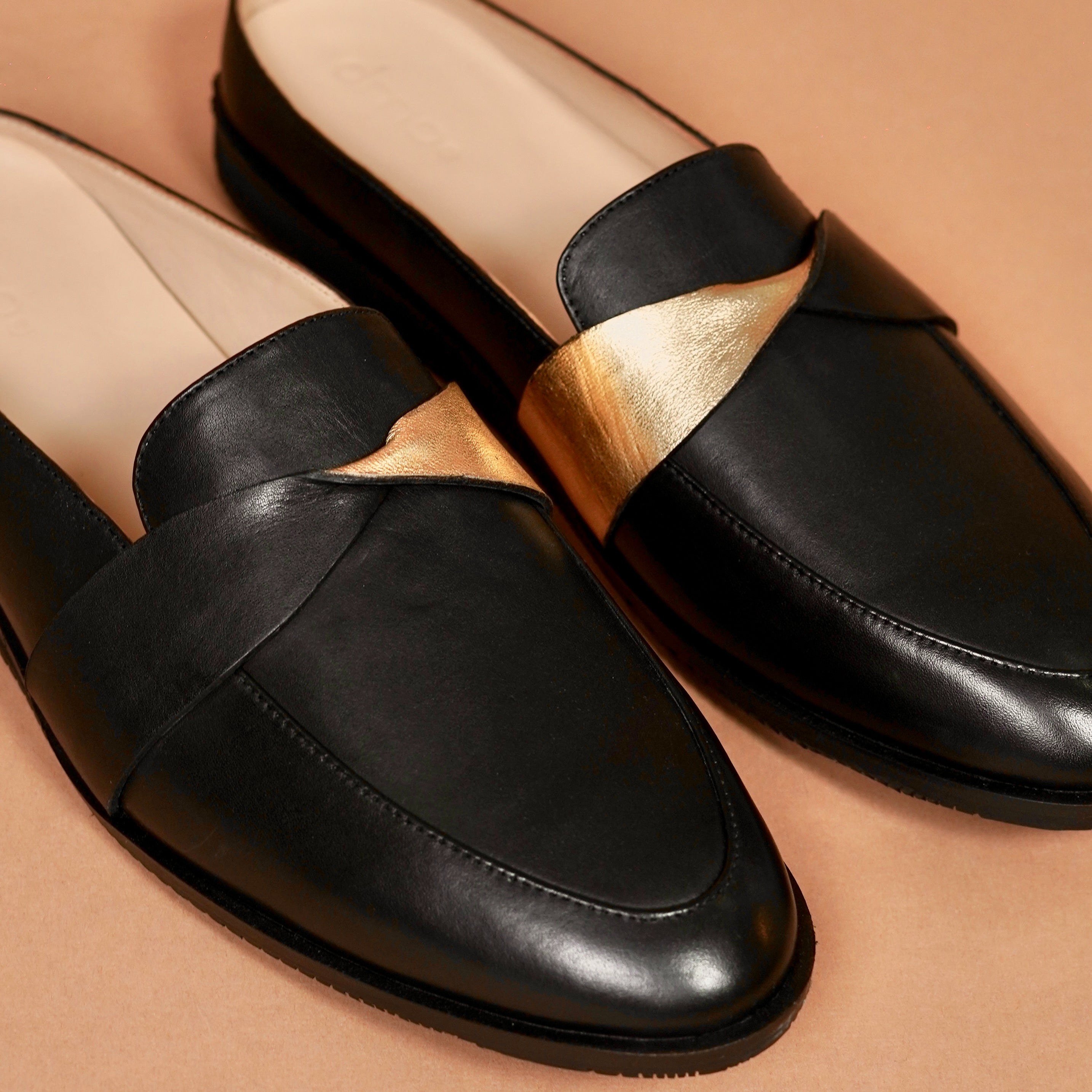 Close-up of gold fold-over panel on black handcrafted leather mule